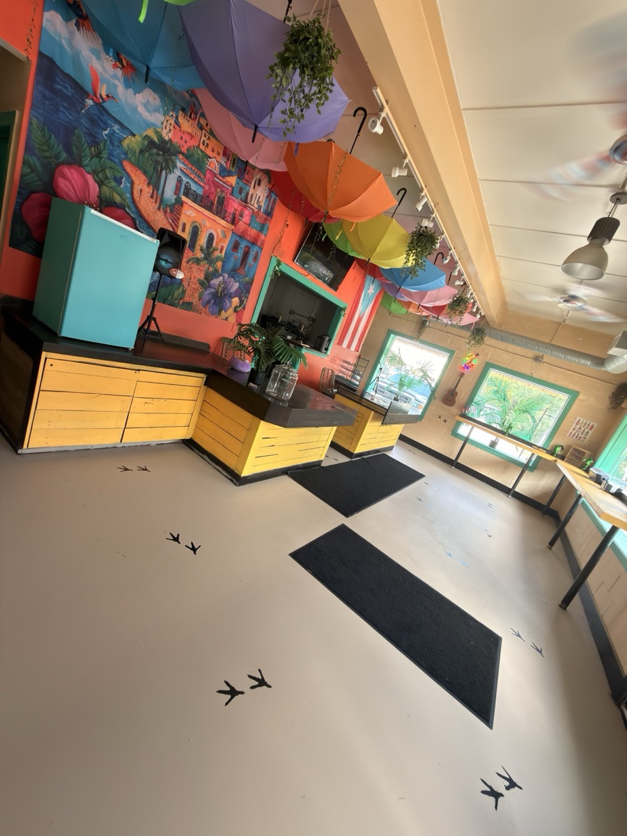 Inside the shop: painted Puerto Rico mural, yellow counters, umbrellas on the ceiling